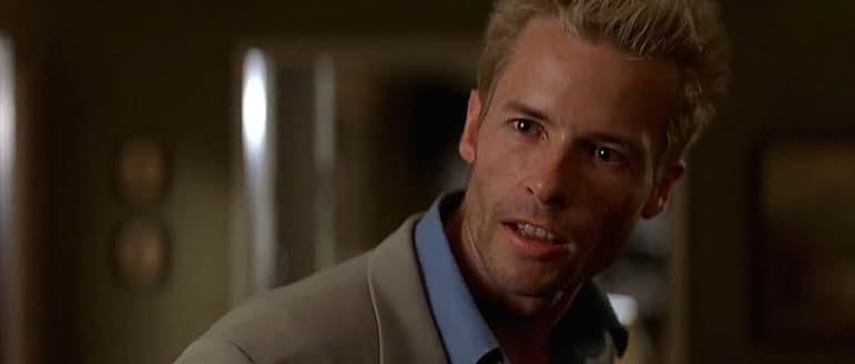 ポラロイド写真を手に持ち、記憶を辿ろうとする険しい表情のレナード