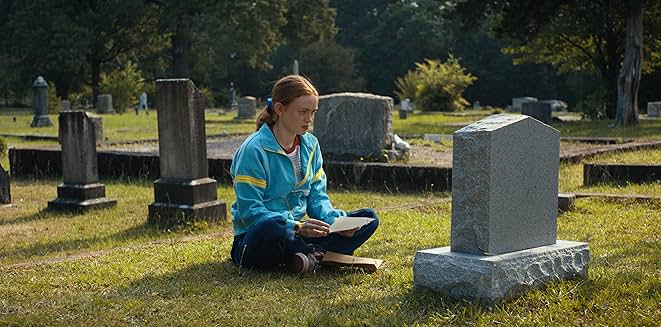 ヘッドホンをして音楽を聴きながら、墓地で兄ビリーの手紙を読むマックス